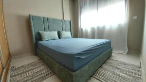 a bed with a headboard in a room with a window at appartement moderne proche aéroport in Derroua +3 photos