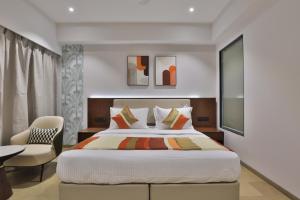 a bedroom with a large bed and a chair at Hotel Elements Surat in Surat