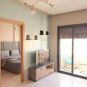 a bedroom with a bed and a tv and a balcony at appartement moderne proche aéroport in Derroua