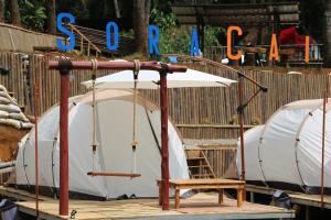 ein weißes Zelt mit einer Schaukel vor einem Zaun in der Unterkunft SoraCai Riverside Campsite in Palayangan