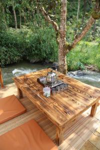 a wooden table with a tea kettle on top at SoraCai Riverside Campsite in Palayangan