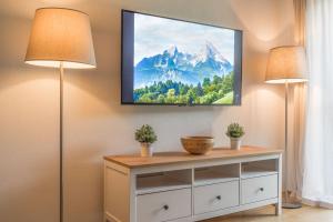a tv hanging on a wall with two lamps at Watzmann Panorama in Berchtesgaden