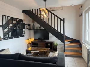ein Wohnzimmer mit einem Sofa, einem TV und einer Treppe in der Unterkunft 207 - Jolie maison mitoyenne entre terre et mer en campagne de Plurien in Plurien