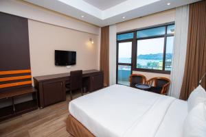 um quarto de hotel com uma cama, uma secretária e uma televisão em Gold Crest Hotel em Mwanza