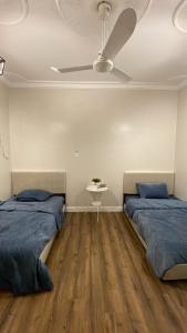 a bedroom with two beds and a ceiling fan at شقة بموقع مميز قريبة من الحرم في قلب المدينة وبجانبها جميع الخدمات in Al Madinah