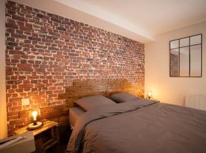 um quarto com uma parede de tijolos e uma cama em L’Auberge de papa 
