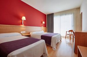 a hotel room with two beds and a red wall at Hotel Surf Mar in Lloret de Mar