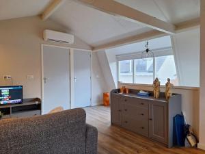 a living room with a couch and a tv at Have a nice stay! - De Pottenbakkerij in Noordwijk