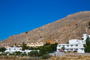 Lindos Portes Suites - Adults Only في ليندوس: مجموعة مباني بيضاء امام جبل