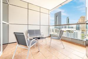 einen Balkon mit 2 Stühlen und einem Tisch auf einem Gebäude in der Unterkunft Elegant 3BR in JBR w/ partial Marina View in Dubai