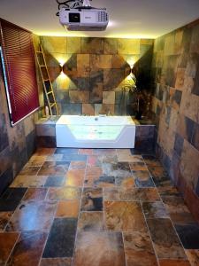 baño con bañera y pared de piedra en Les Charmes-Balnéothérapie-Vidéoprojecteur-Netflix, en Baume-les-Dames
