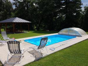 two chairs and a swimming pool with a gazebo at Apartmány U Potoka in Dolní Moravice