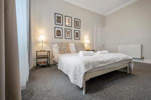 a white bedroom with a large bed and two lamps at Beautiful Apartment with Parking in Hexham