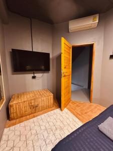 a bedroom with a bed and a tv and a door at Hostel Friends Station & Cafe in Pattaya South