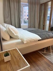 Una cama con almohadas blancas y una mesa en una habitación en BOHO Cane Apartment, en Tirana