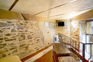 Zimmer mit einer Steinmauer, einer Bank und einem Fenster in der Unterkunft Appartamento dei Raspi d'uva in Apricale