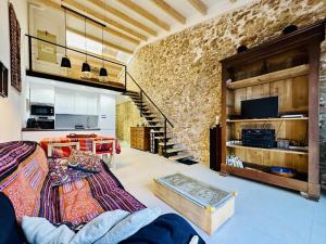 a living room with a stone wall and a staircase at Pecher CostaBravaSi in Sant Feliu de Guíxols