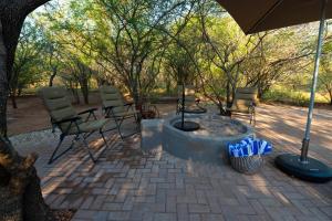 a fire pit with chairs and an umbrella at Bushveld Jewel - Close to Kruger in Hoedspruit