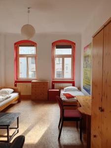 a room with two beds and a table and two windows at Kulturschutzgebiet in Dresden