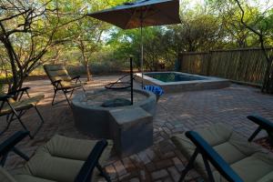 a patio with a fire pit with chairs and an umbrella at Bushveld Jewel - Close to Kruger in Hoedspruit