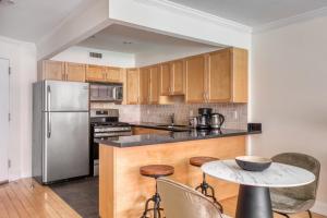 La cuisine est équipée d'armoires en bois et d'un réfrigérateur en acier inoxydable. dans l'établissement Nolita 1BR w Elevator Roof Deck nr SoHo NYC-907, à New York