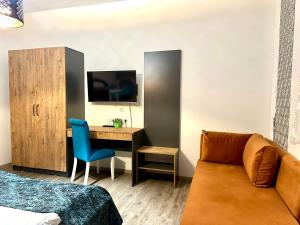 a room with a couch and a desk with a tv at Pension Kristalpark in Günzburg