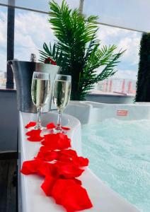 a table with two wine glasses and red flowers at Hotel Nevis Wellness & SPA in Oradea