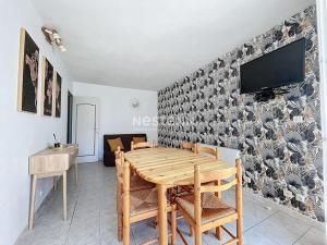 een eetkamer met een tafel en een tv aan de muur bij 3192- T2 à 400m de la plage in Argelès-sur-Mer