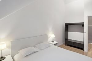 ein weißes Schlafzimmer mit einem weißen Bett und einem TV in der Unterkunft Apartment in Brussels, Degroux by Homenhancement SA in Brüssel