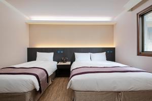 2 bedden in een hotelkamer met 2 bedden van 6 x 7 cm bij 沫秋立柳川行旅 in Taichung