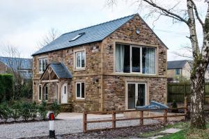 a brick house with a wooden fence in front of it at Bramley Brook Cottage 5* Luxury in Whalley