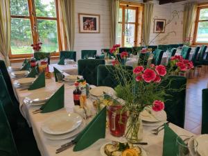 einen langen Tisch mit Tellern und Blumen in einem Zimmer in der Unterkunft Hotelik ze śniadaniami "KUR" Myszyniec-Kurpie in Myszyniec