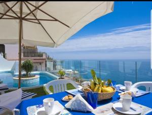 a blue table with a bowl of fruit and an umbrella at Holidays dream Praiano in Praiano