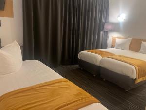 a hotel room with two beds and curtains at Hotel Premium in Forbach