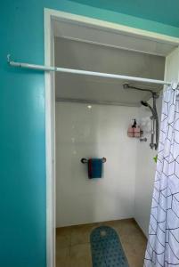bagno con tenda doccia blu e sedia di Matauri Bay Shearer's Cottage a Matauri Bay