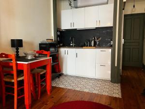 une cuisine avec des placards blancs, une table rouge et des chaises dans l'établissement Chez Frida, au Puy-en-Velay