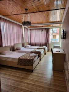 three beds in a bedroom with a wooden ceiling at Hotel Elio in Batumi