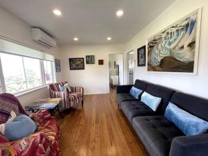 Matauri Bay的住宿－Matauri Bay Shearer's Cottage，客厅配有黑色真皮沙发和椅子