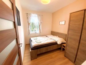 niewielka sypialnia z łóżkiem i oknem w obiekcie Chalet 3 Domky 182 w Demianowskiej Dolinie