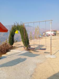 an empty playground with a swing set and trees at Ihram Hotel And Guest House in Swat