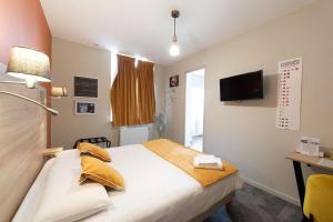a hotel room with a bed and a television at Logis - Hostellerie & Restaurant du Marché in Le Cateau