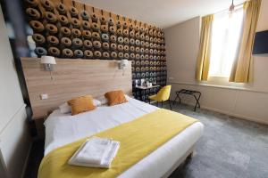 a bedroom with a large white bed with yellow sheets at Logis - Hostellerie & Restaurant du Marché in Le Cateau