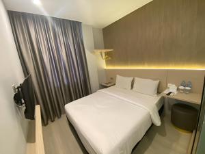 een hotelkamer met een wit bed en een bureau bij Swasana Hotel Medan in Medan