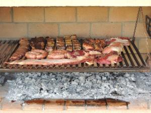 a grill with meat and other food on it at La Ribera Home & Rest Mendoza in Maipú
