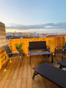 eine Holzterrasse mit Stühlen und Tischen auf dem Balkon in der Unterkunft Honoré - Rooftop- Centre Vieux Port in Marseille