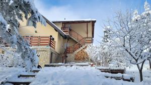 una casa cubierta de nieve con escaleras y árboles en Zlatibor Apartmani DM Tornik en Zlatibor