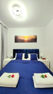a bedroom with a blue bed with two towels on it at Apartament Perła Jantaru by TriApart in Jantar