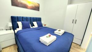 Un dormitorio con una cama azul con toallas. en Apartament Perła Jantaru by TriApart en Jantar