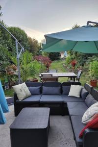 patio con divani, tavolo e ombrellone di L'Écrin Savoyard a Bonne-sur-Ménoge