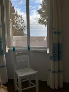 una sedia bianca seduta davanti a una finestra di Seaview Villa Lazzaretto a Fertilia